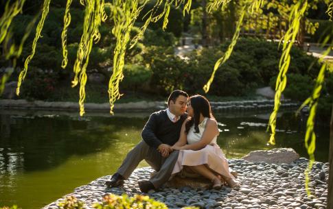A couple sits on black rock beach in the Japanese Garden.