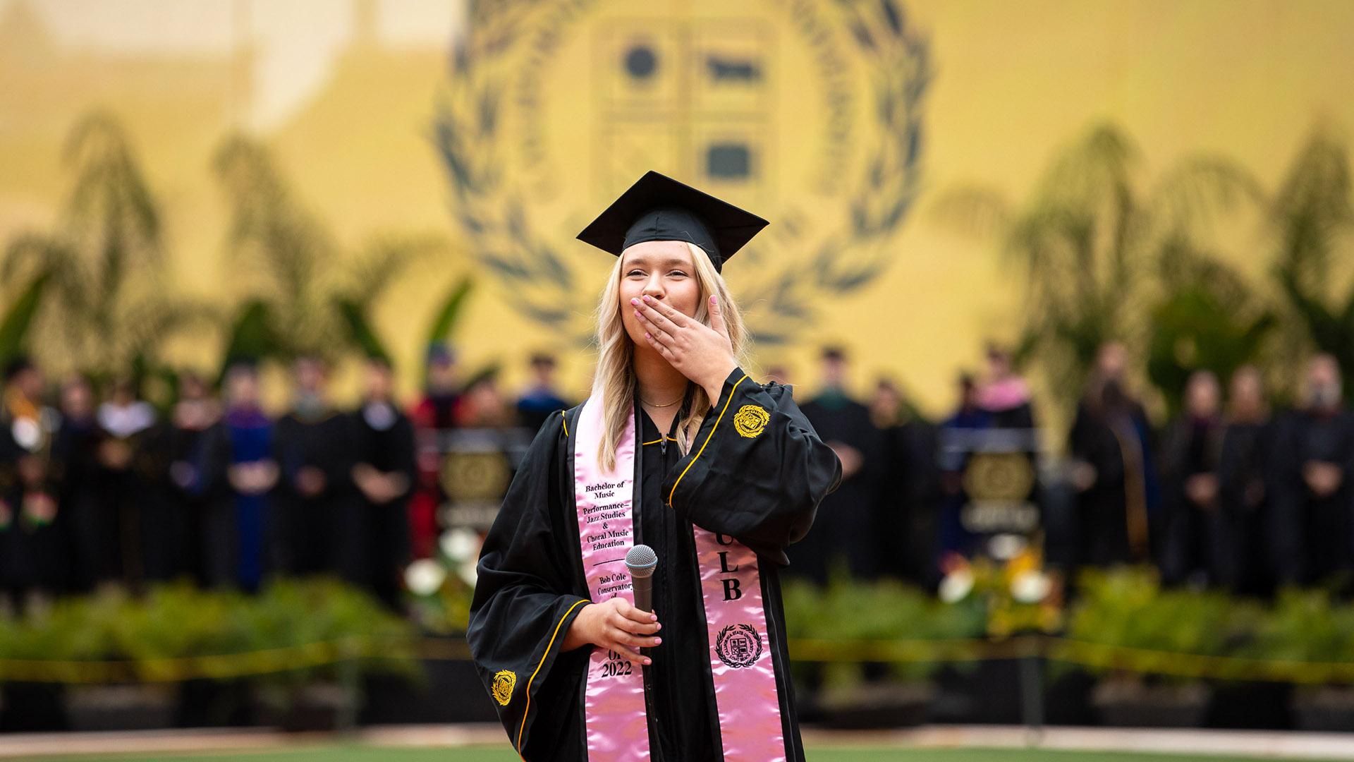 Female graduate blows a kiss in front of CSULB Commencement stage