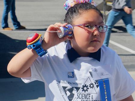 child holding a string telephone to their ear