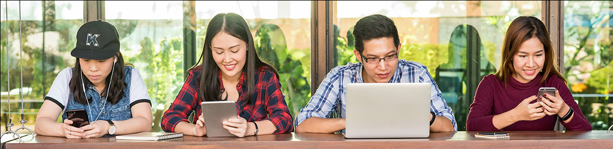 students at a table looking at devices