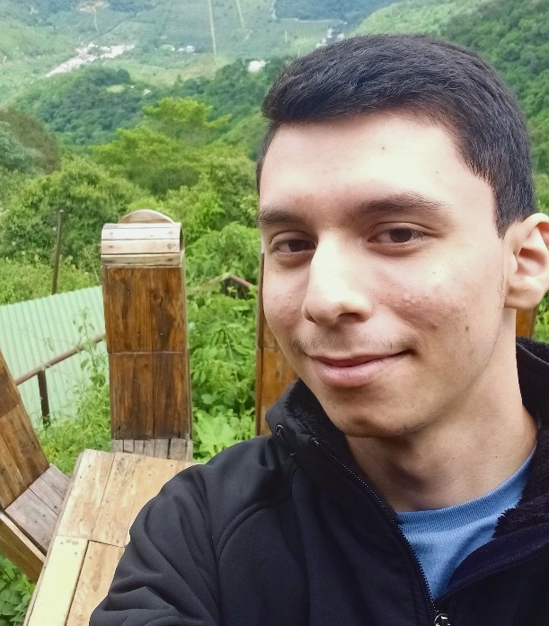 A selfie taken of Alderix Campos overlooking a green landscape