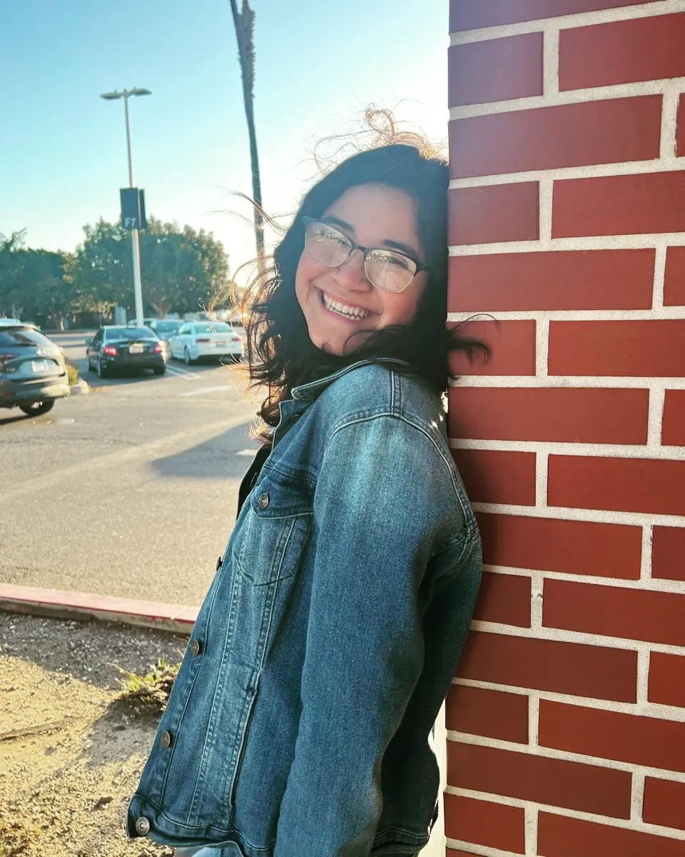 A photo taken of Laura Escobar, leaning against a brick wall.