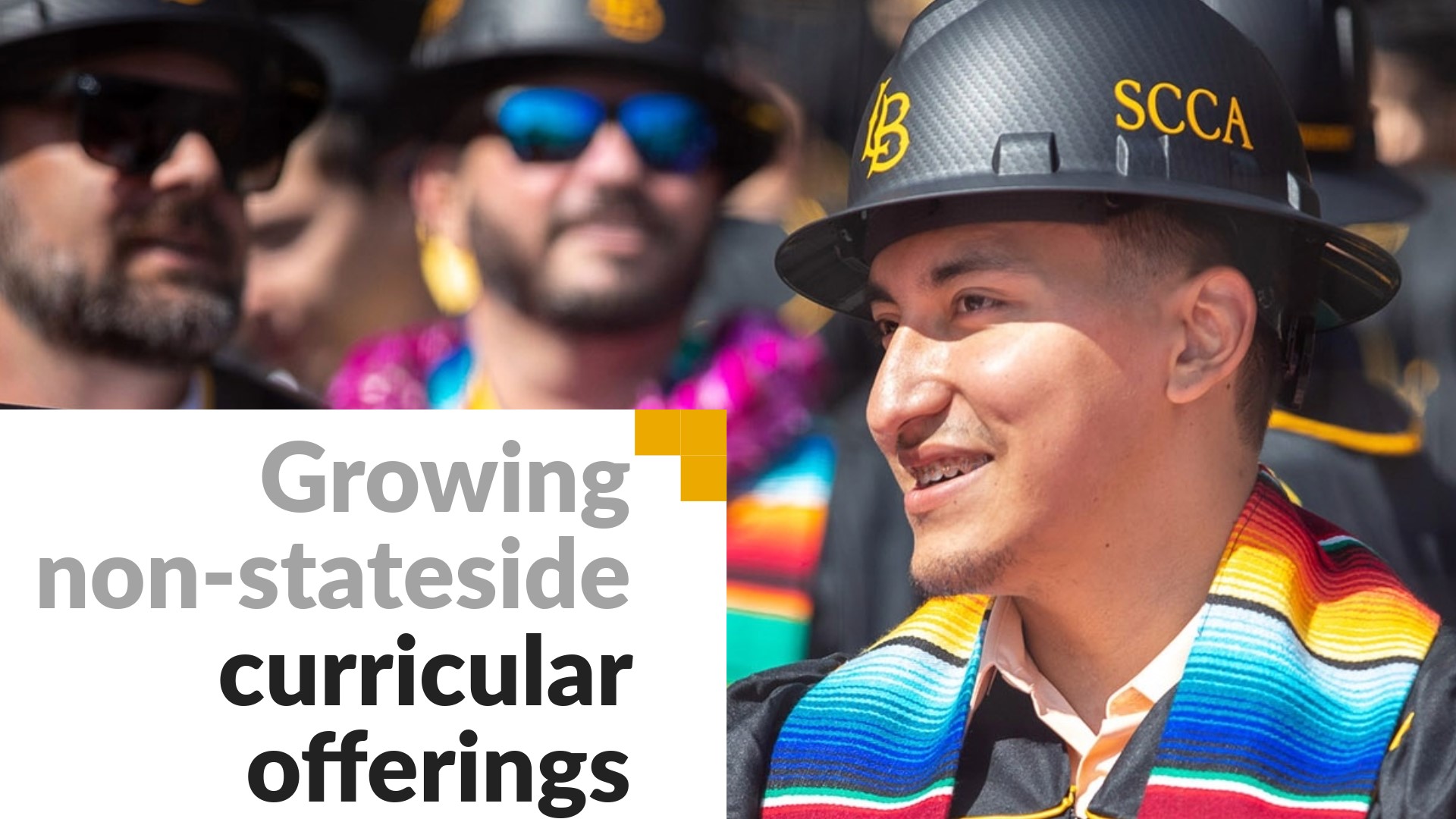Growing non-stateside curricular offerings. Image shows a student in a construction hat at commencement.. 