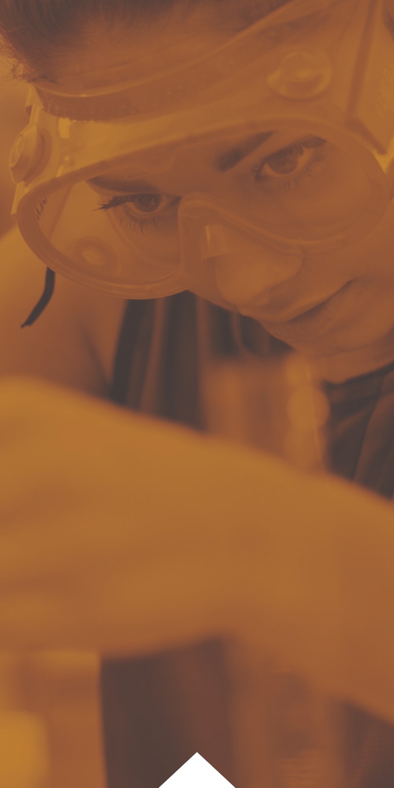 A student in safety goggles works in a lab. 