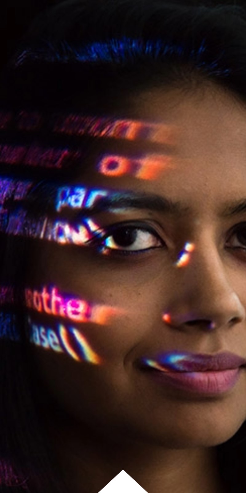 A woman with code illuminated on her face smiles at the camera. 