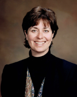 Smiling white woman with short brown hair, black jacket, colorful scarf