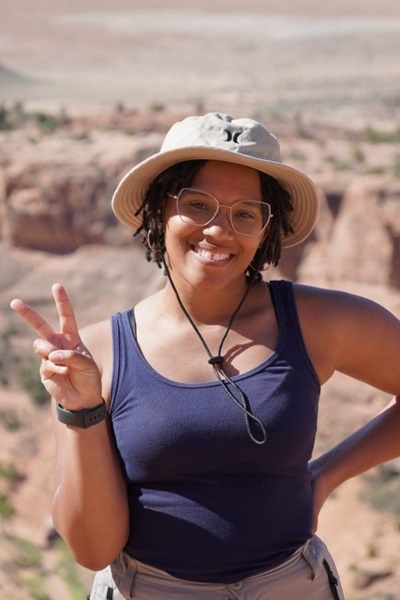 Mikaela Williams standing in a desert holding up two fingers