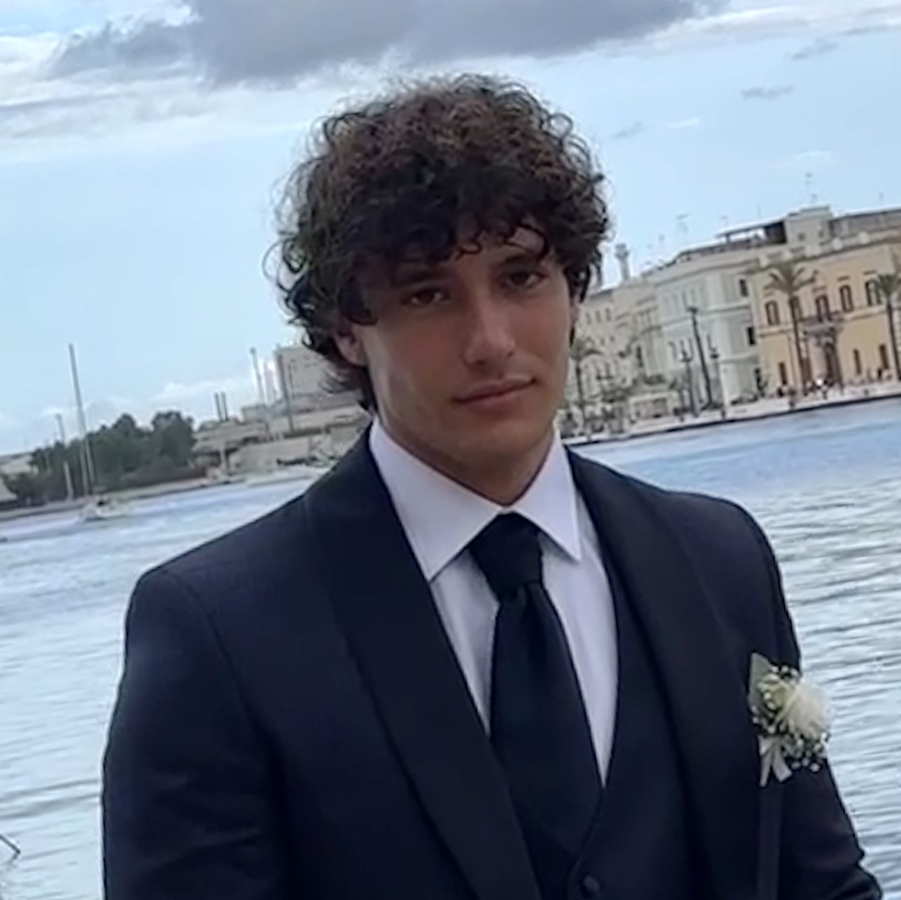 male in suit standing in front of water