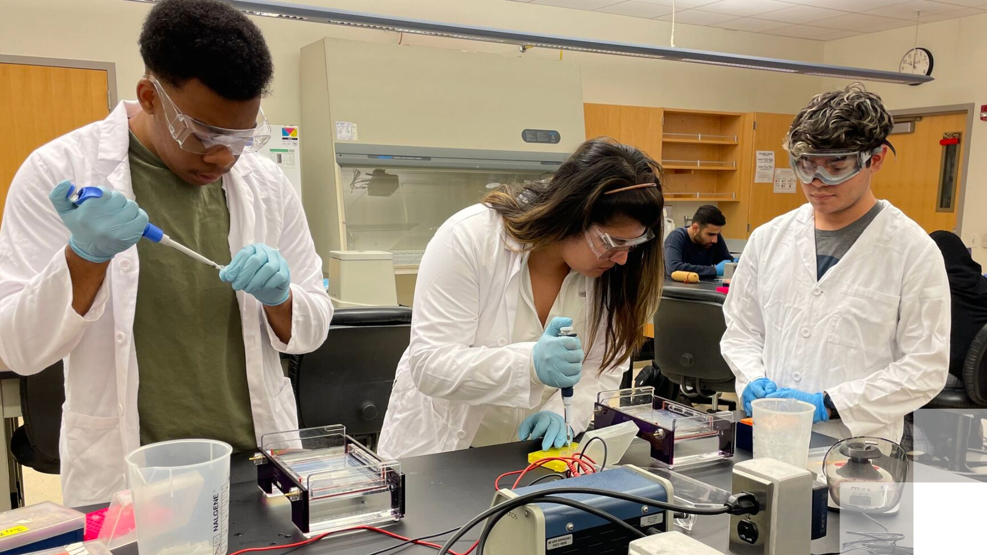 Students in white coats conduct chemistry experiments. 