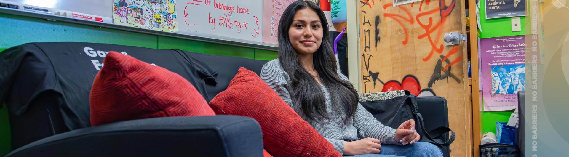 A latinx student sitting on a couch of the Latine Resource Center