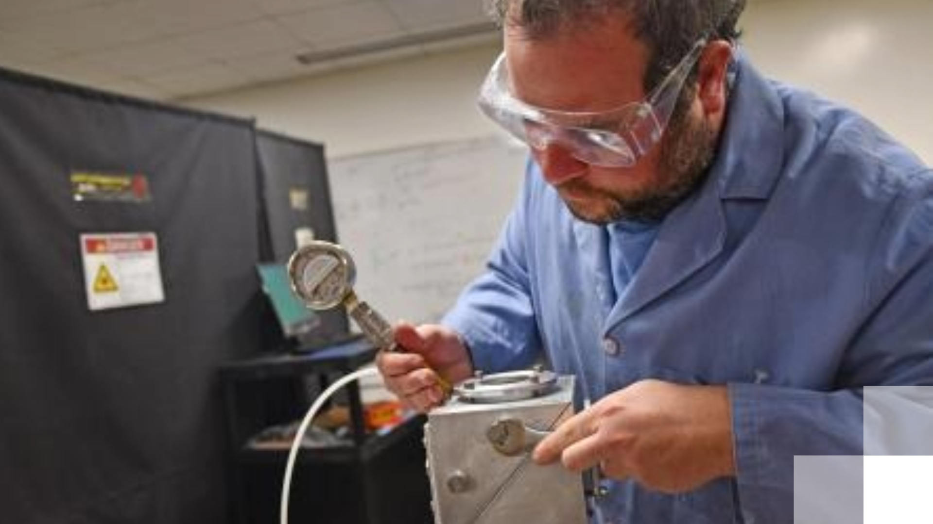 A professor wearing safety goggles conducts research.