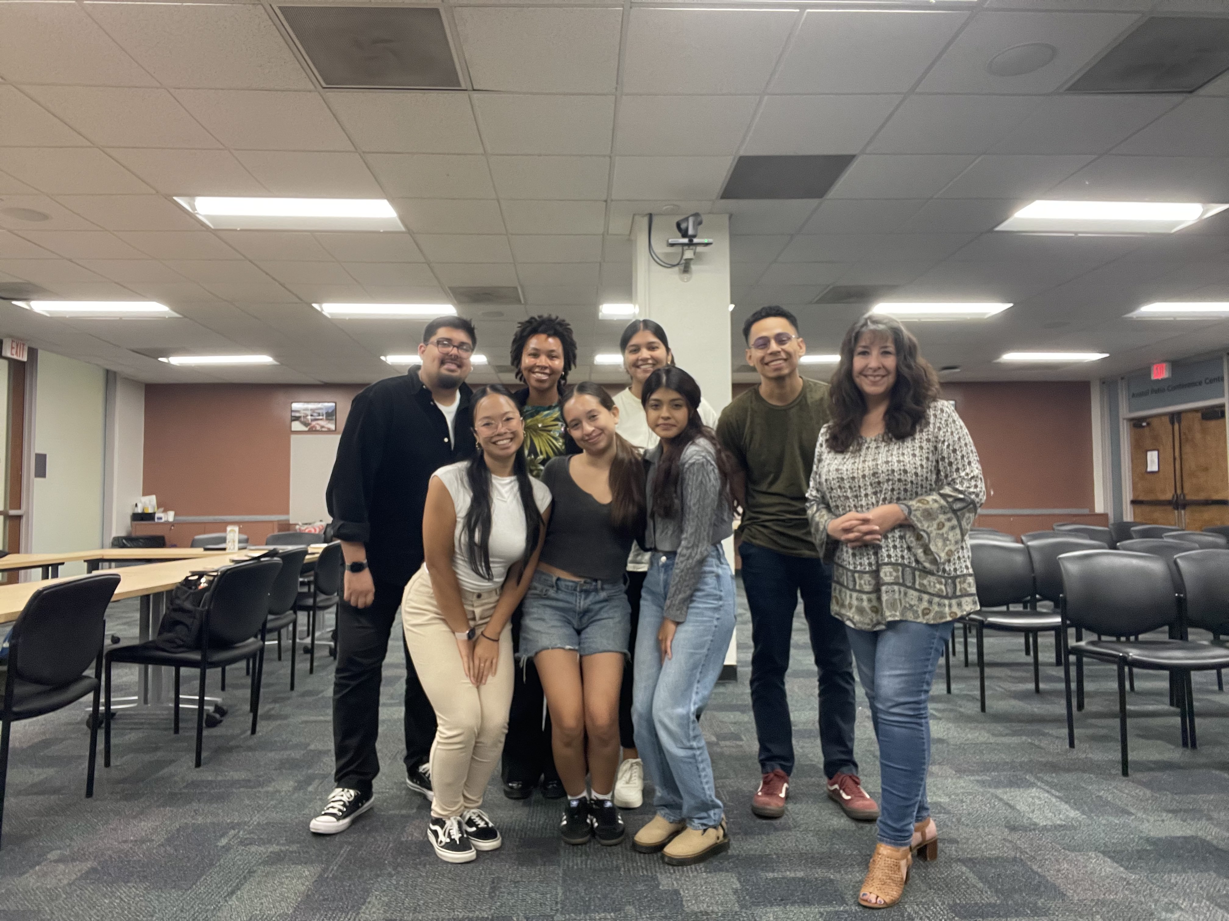 group of seven students huddled for a photo in the Anatol Center for the amplifying student voices column