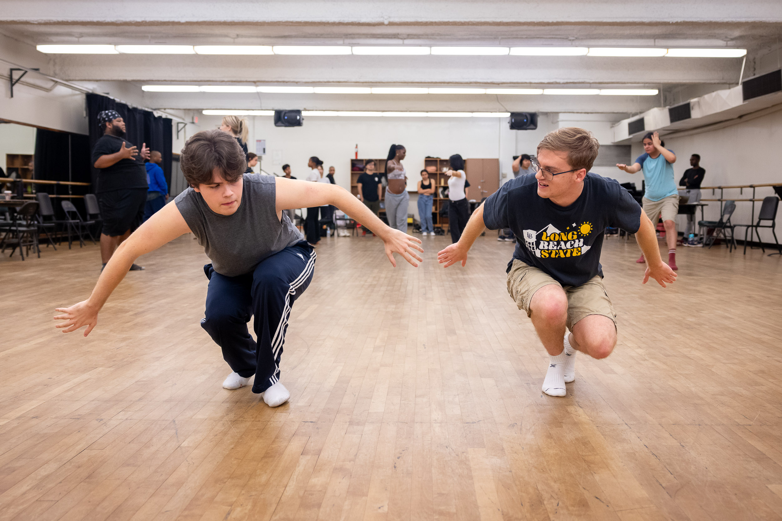 Two theater students doing movements on a wooden floor