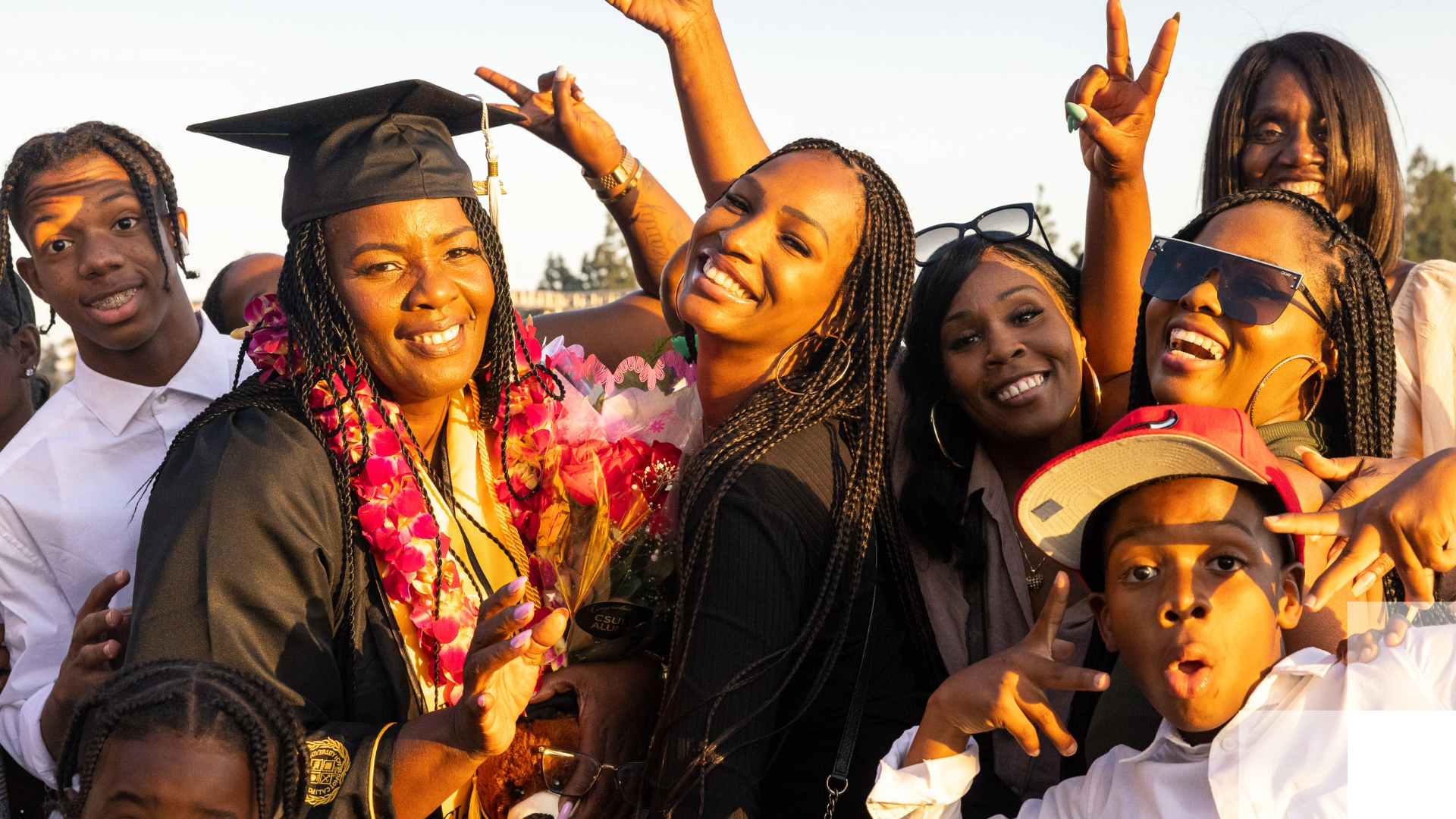 Two graduates and their families smile after graduation. 