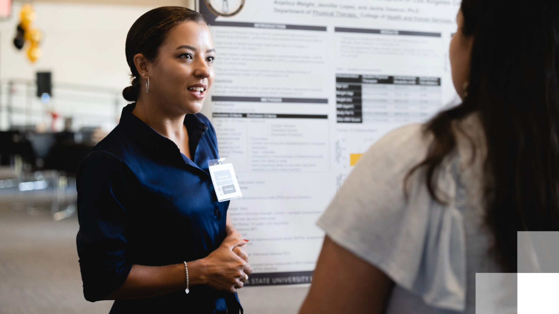 Woman with nametag stands in front of posterboard.