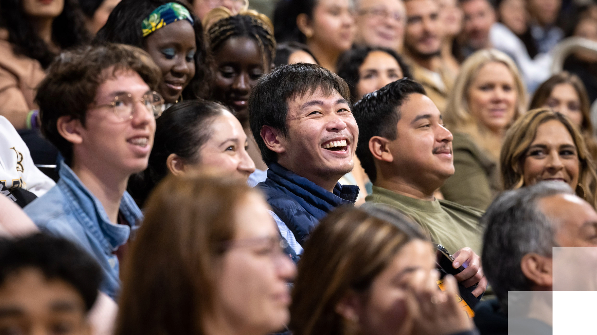 A crowd listens and smiles. 