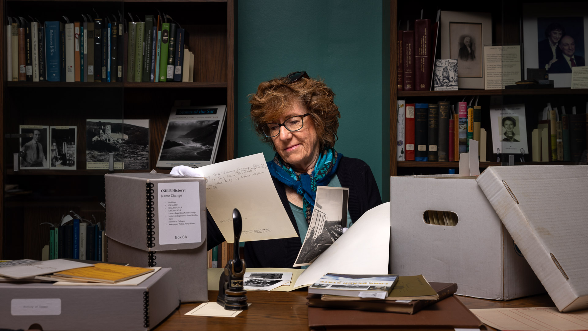 Author Barbara Kingsley-Wilson sits at a table looking at archival documents in the University Library