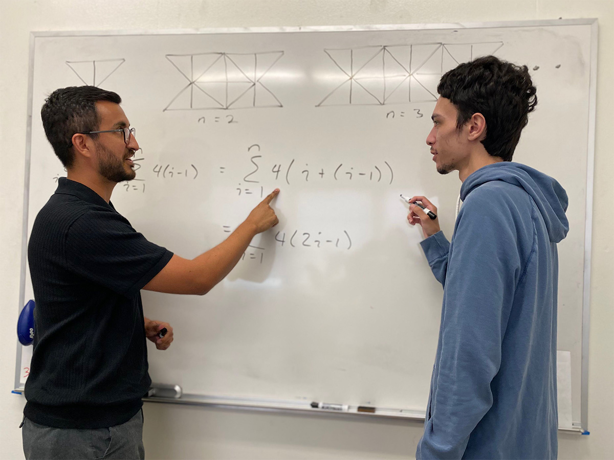 Dr. Martinez and student discussing math problem on whiteboard