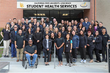 a group of people posing for a photo in front of student health service