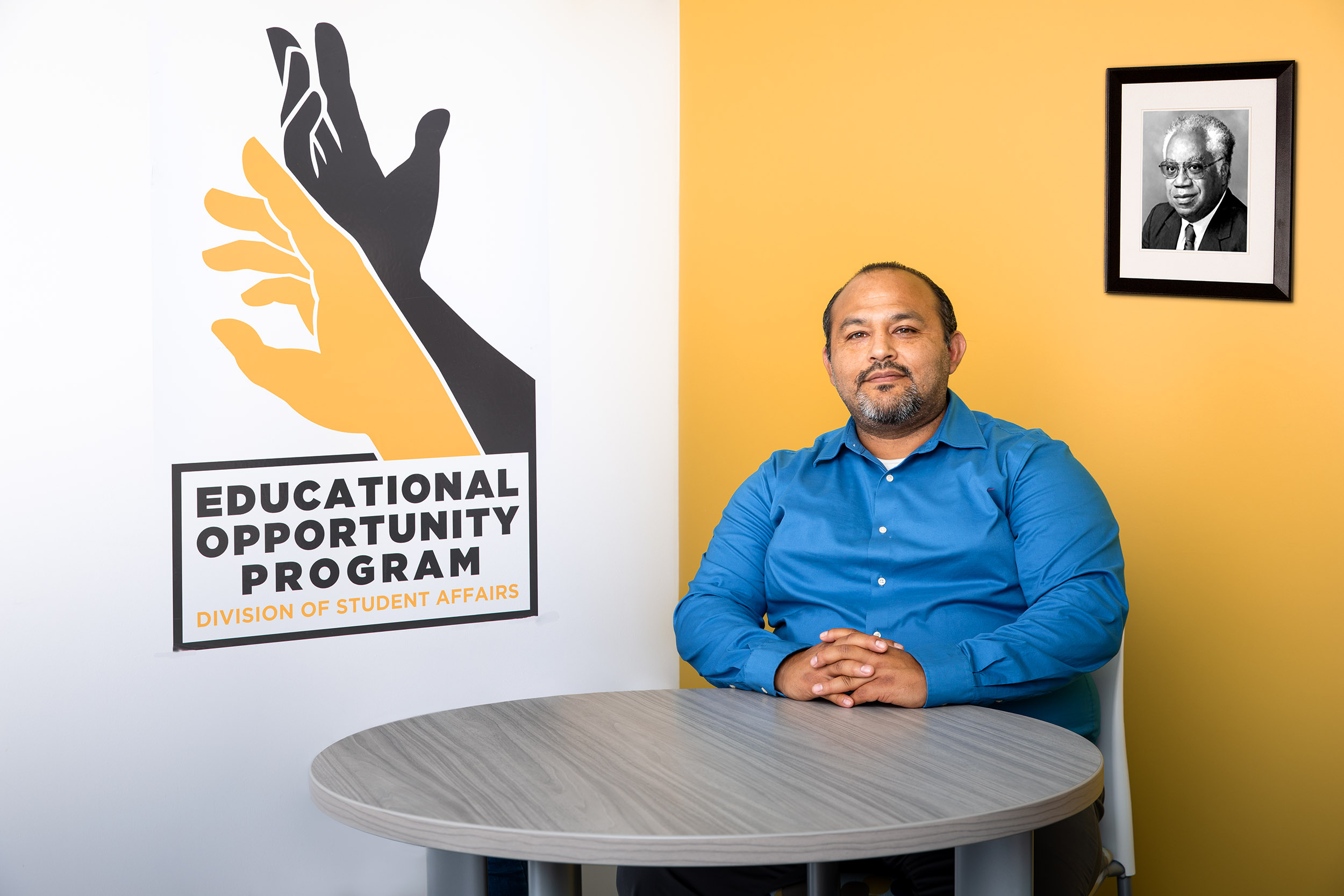 EOP Director Eduardo Leyva sitting at a table in front of a framed photo of EOP founder Joseph White