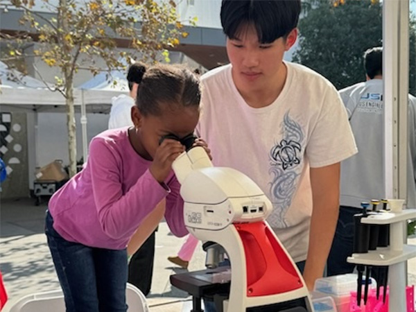 young child looking through a microscope