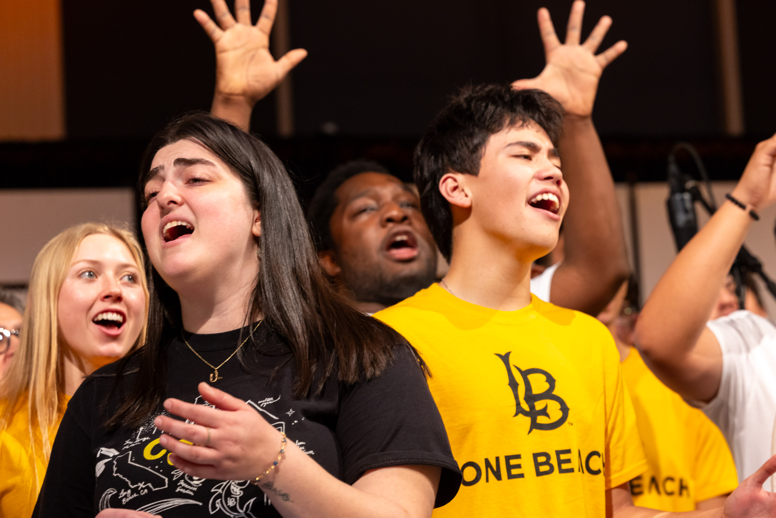 Choir members sing with passion, some raising their hands in worship at the Community Gospel Choir Concert.