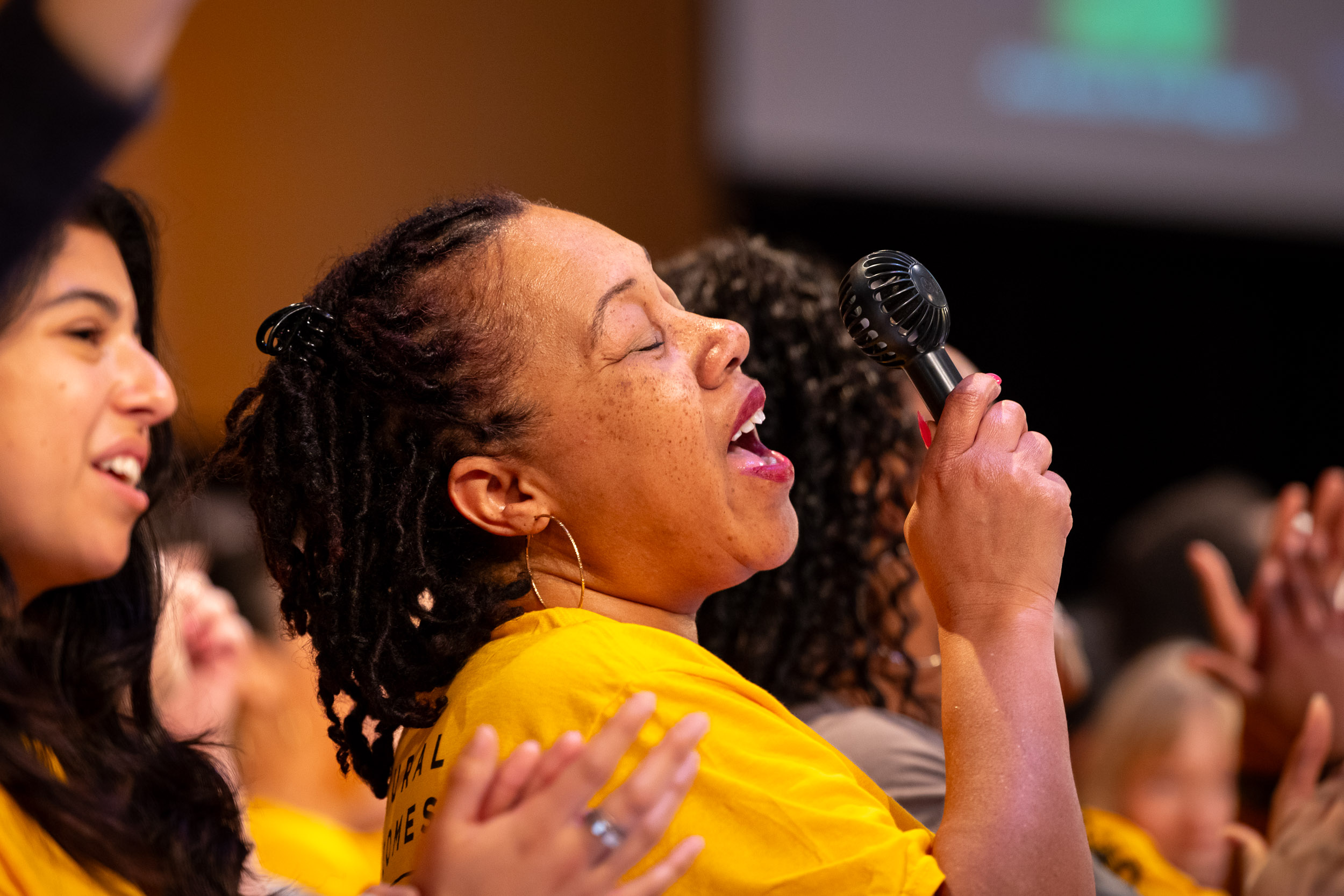 A performer stands onstage holding a microphone during Community Gospel Choir Concert