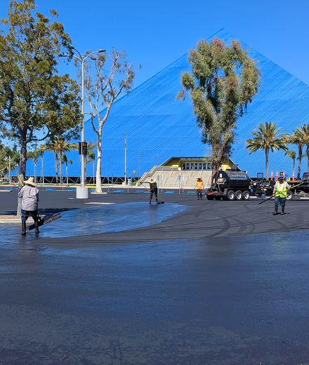 Workers repaving a parking lot in front of Walter Pyramid