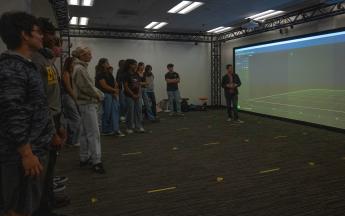 students standing in front of a large screen