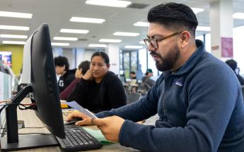 Male Student in COB LAB helping with a Lady with Tax Service