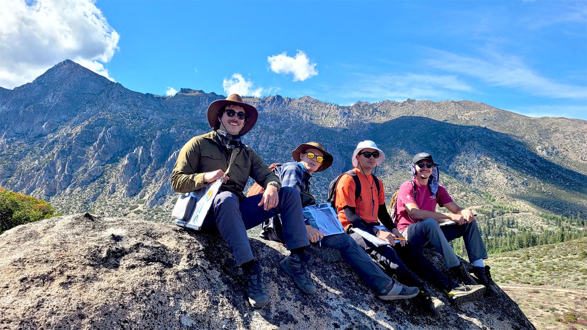 Students sitting on mountain ledge