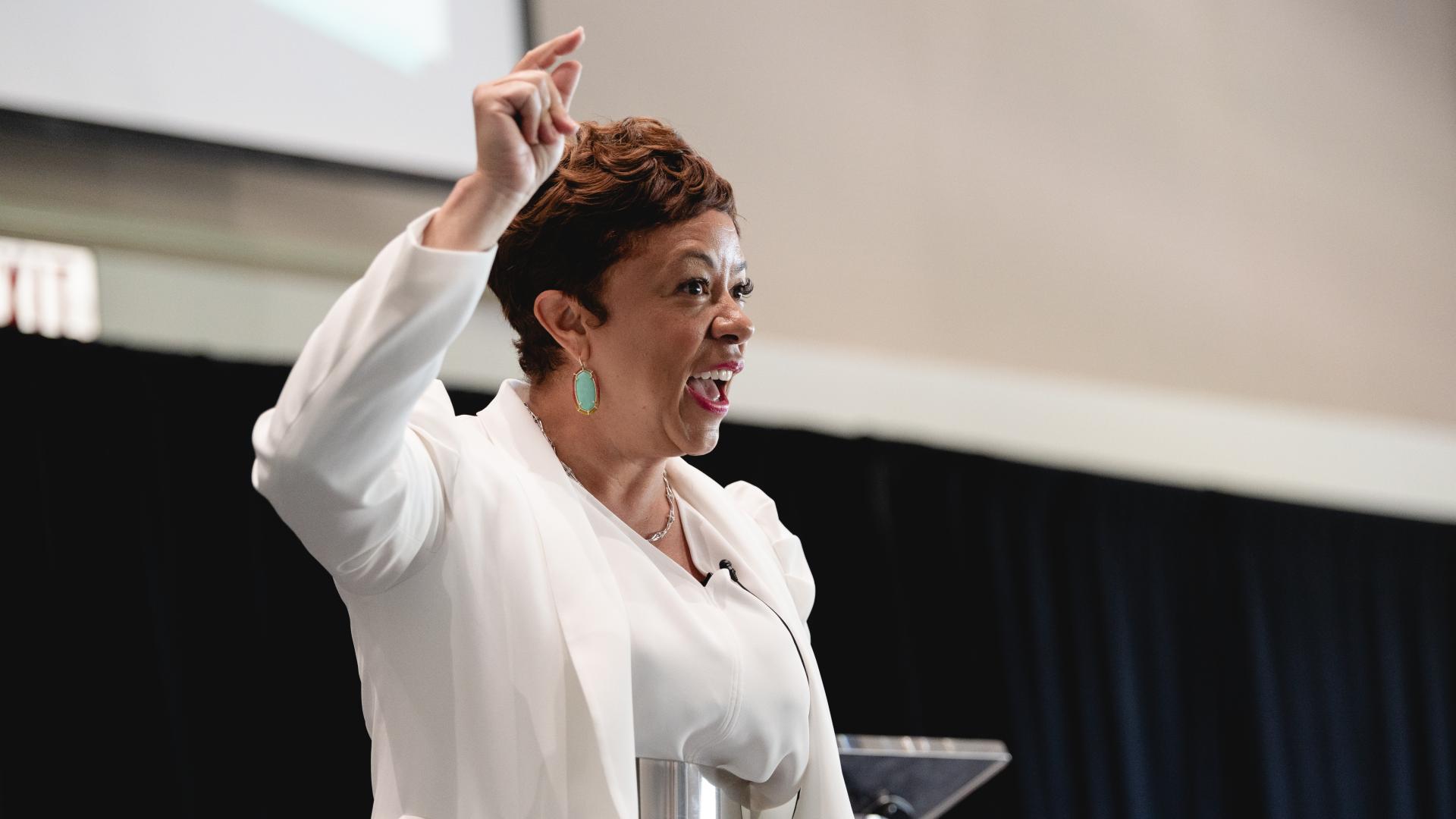 Confident woman speaking passionately on stage at a conference.