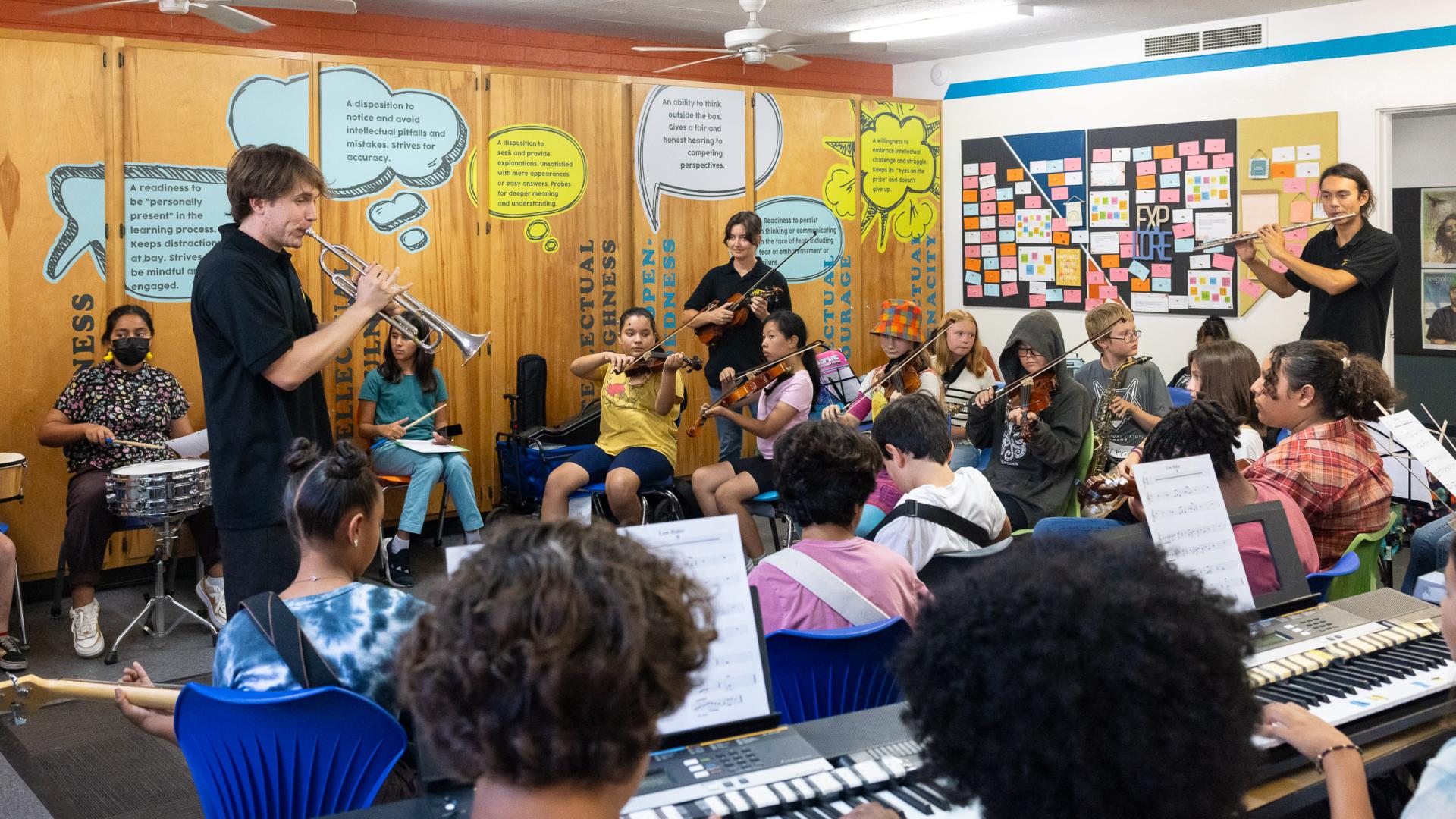 Ben Rifkin plays a trumpet while teaching young music students