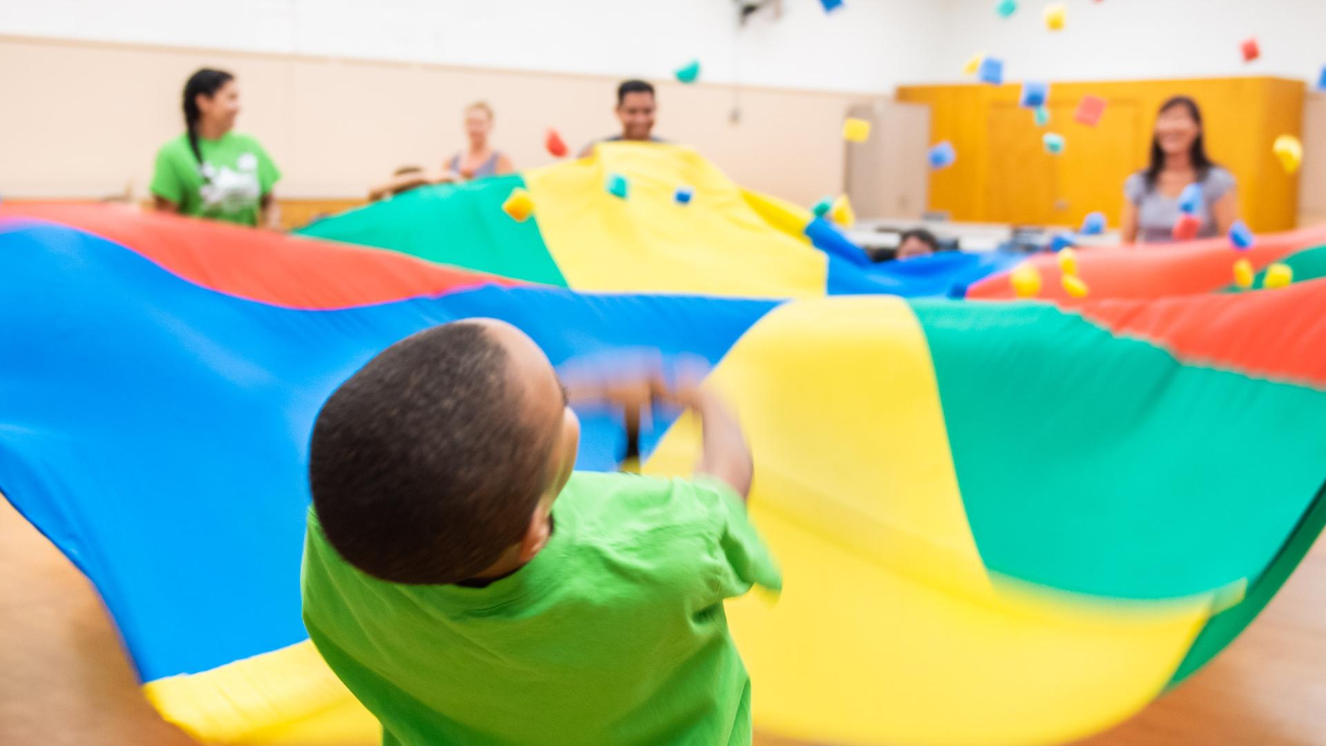 Children play under rainbow tarp