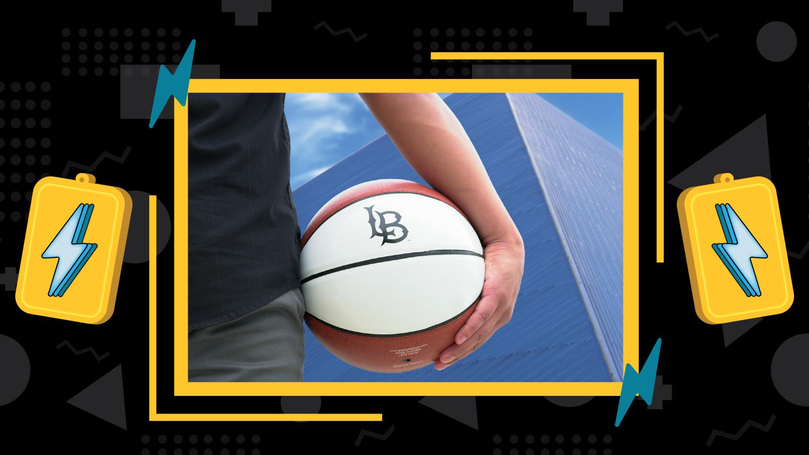 Zoomed in angle of a persons arm holding the LB Basketball with the pyramid at CSULB in the background.