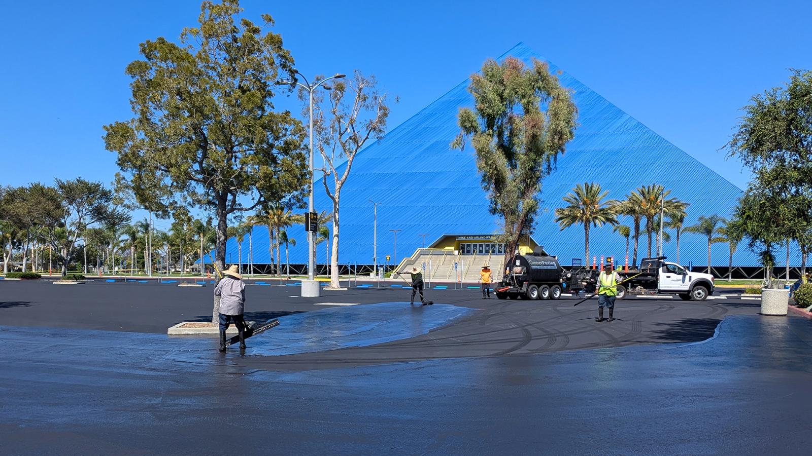 Workers repaving a parking lot in front of Walter Pyramid