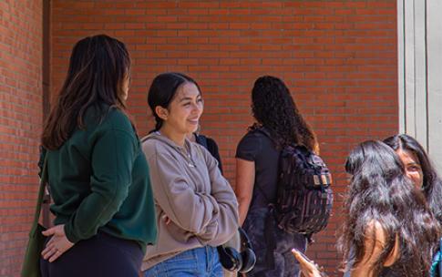 CSULB students have a conversation in a hallway on campus.