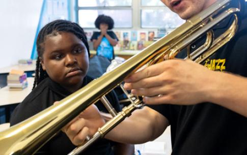 CSULB student Ben Rifkin, with trombone, interacting with a girl at a music class