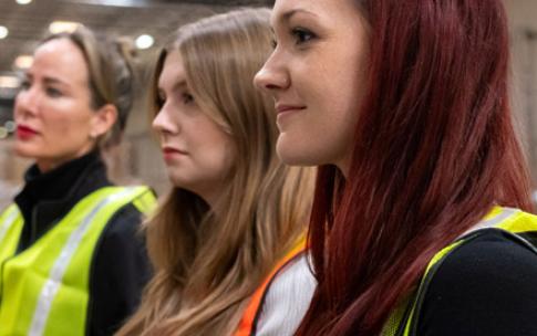 A faculty member and students wearing safety vests while touring a distribution center