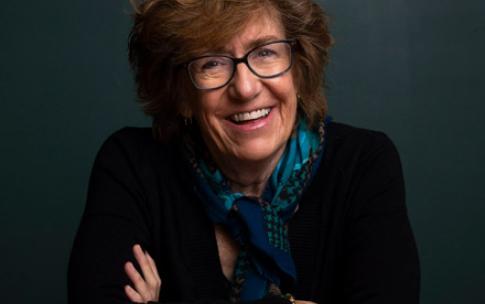 Author Barbara Kingsley-Wilson sits smiling at a table with her arms crossed in front of her.