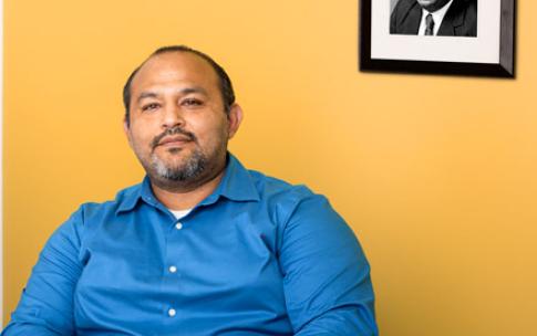 EOP Director Eduardo Leyva sitting in front of a framed photograph of EOP founder Joseph White