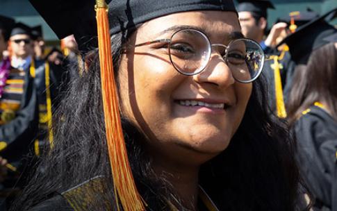Hispanic female graduate smiles as she watches Commencement