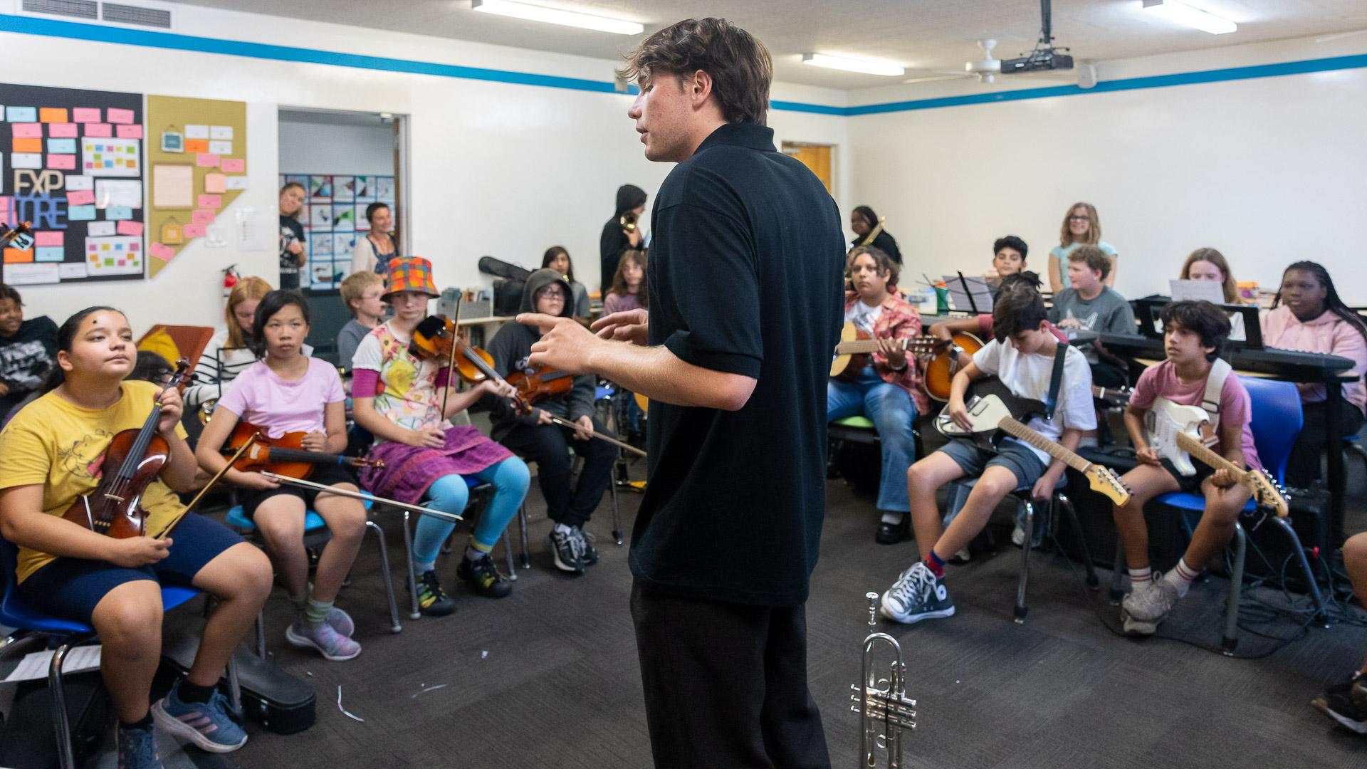 Ben Rifkin teaching music in a classroom filled with children holding musical instruments