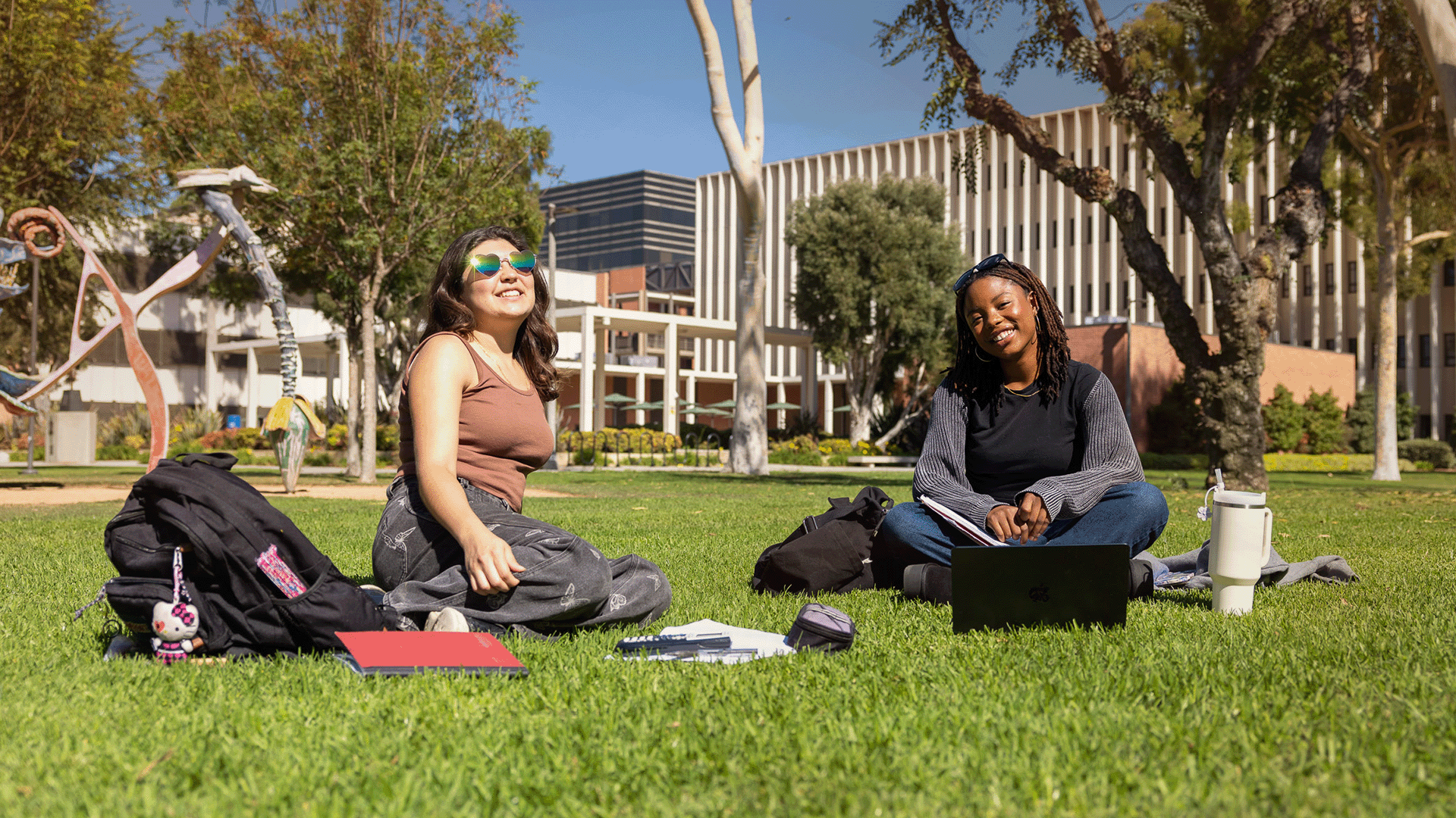 Two students sitting on a campus lawn