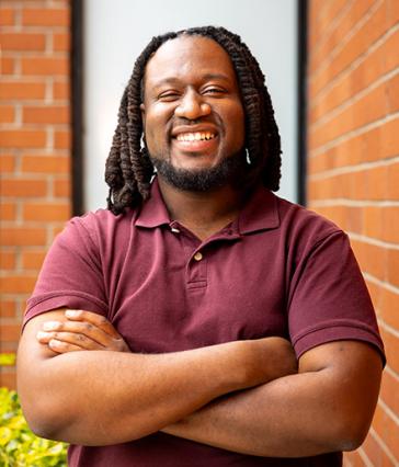 Joshua James, a recipient of the Black Alumni Scholarship, smiling with arms crossed