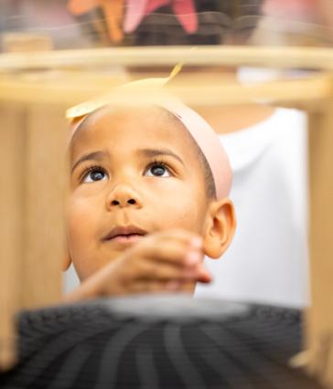 A young girl peers up at an experiment at the Science Learning Center.