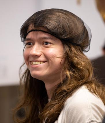 A Summer LIFE student with long hair wears a hairnet and smiles.