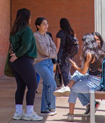 CSULB students have a conversation in a hallway on campus.