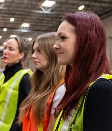 A faculty member and students wearing safety vests while touring a distribution center