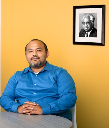 EOP Director Eduardo Leyva sitting in front of a framed photograph of EOP founder Joseph White